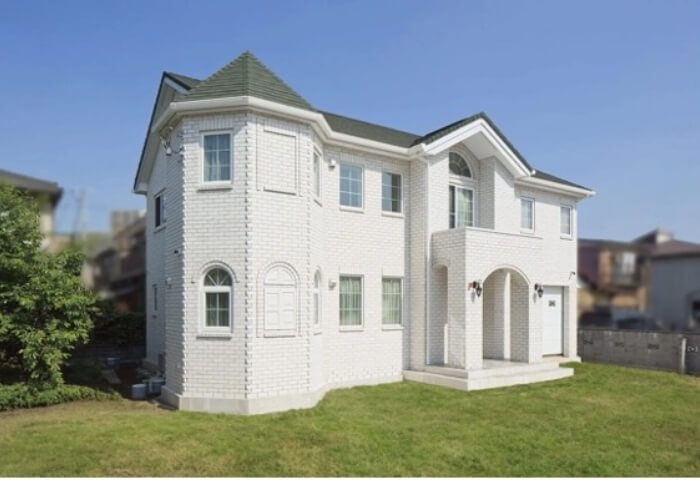 優美さ漂う白亜のお城のようなレンガ積みの家の写真